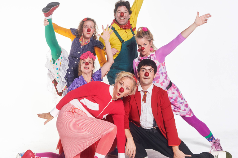 Sechs bunt angezogene ROTE NASEN Clowns auf einem Gruppenfoto.