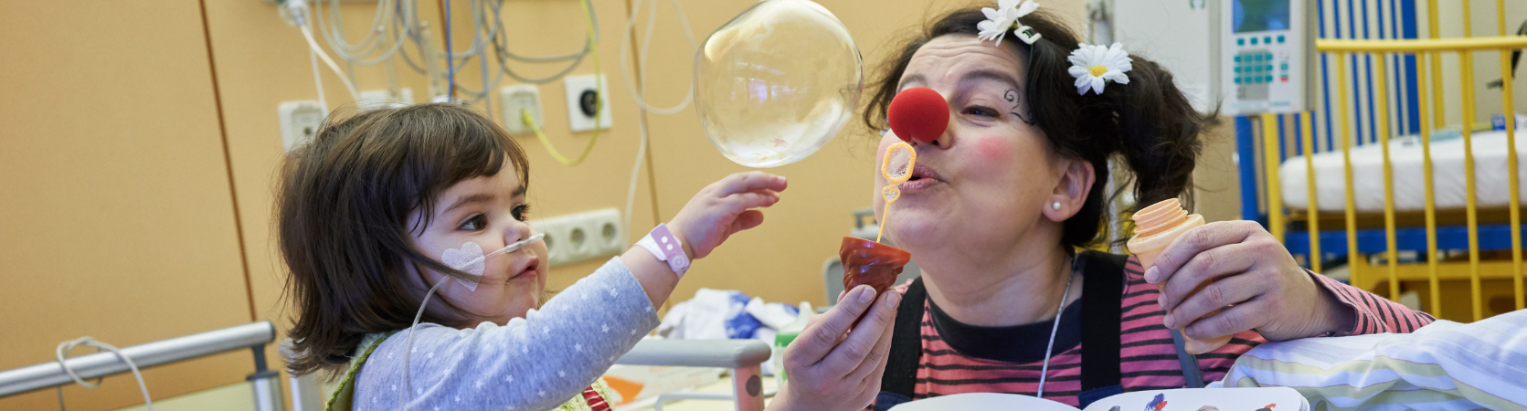 Ein ROTE NASEN Clown bläst eine Seifenblase für ein kleines Mädchen. 